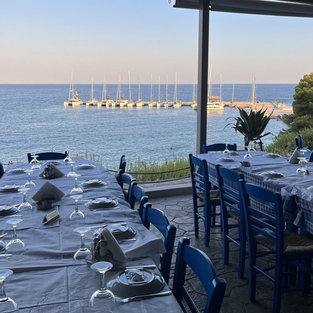 Restaurant table set overlooking sailing boats in bay below