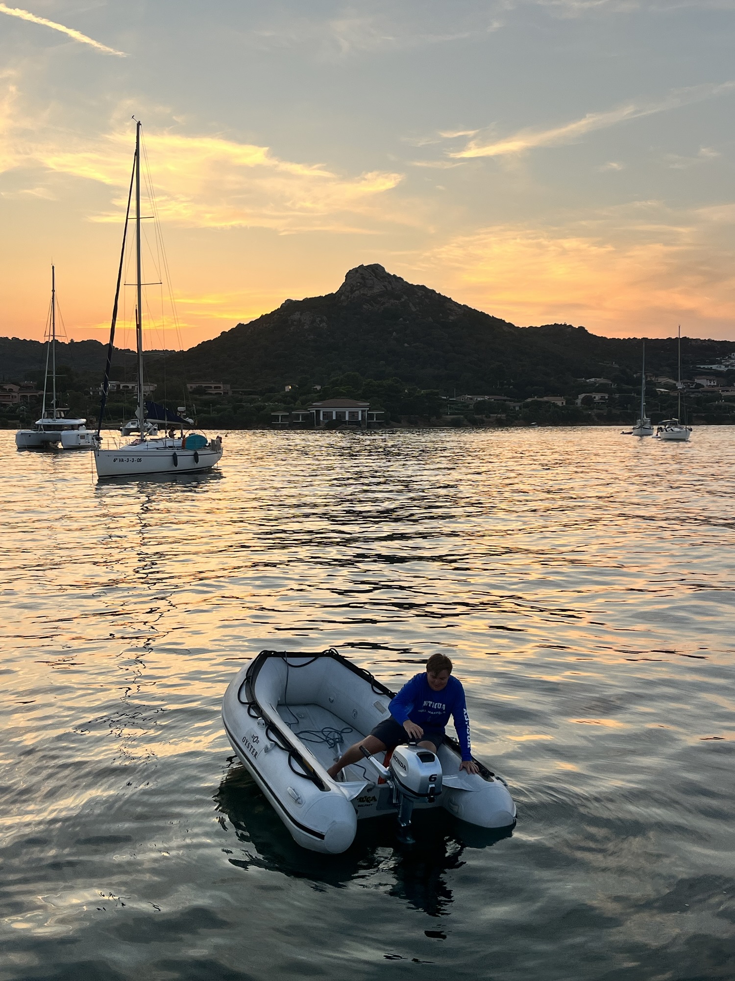 Nathan in the dinghy at sunset in Sardinia